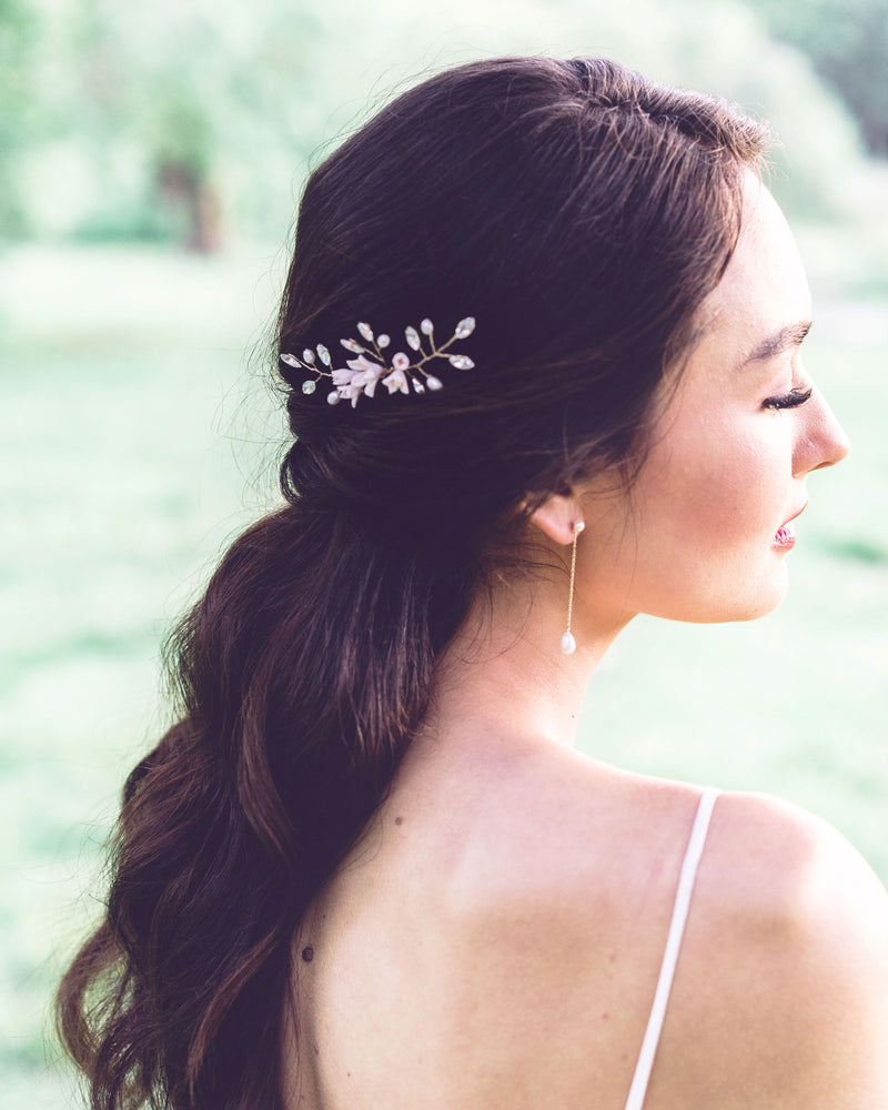 A bride wears Teardrop Pearl Long Earrings, paired with a hair pin of pearls, crystals, and flowers.
