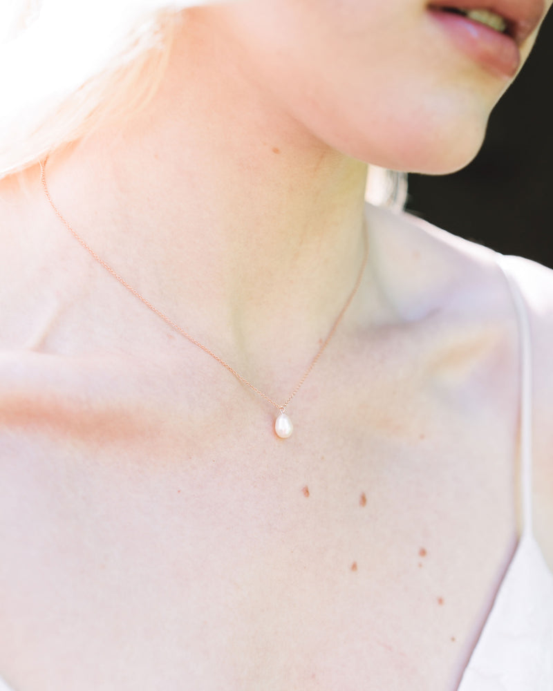 A bride wears a classic Teardrop Pearl Bridal Necklace in rose gold.