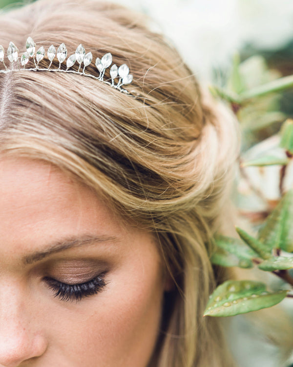 Close view of a bride wearing an understated bridal crown of petite crystal leaves.