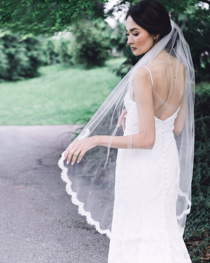 A bride wears the Wister Veil; a fingertip veil with lace starting at the elbow.