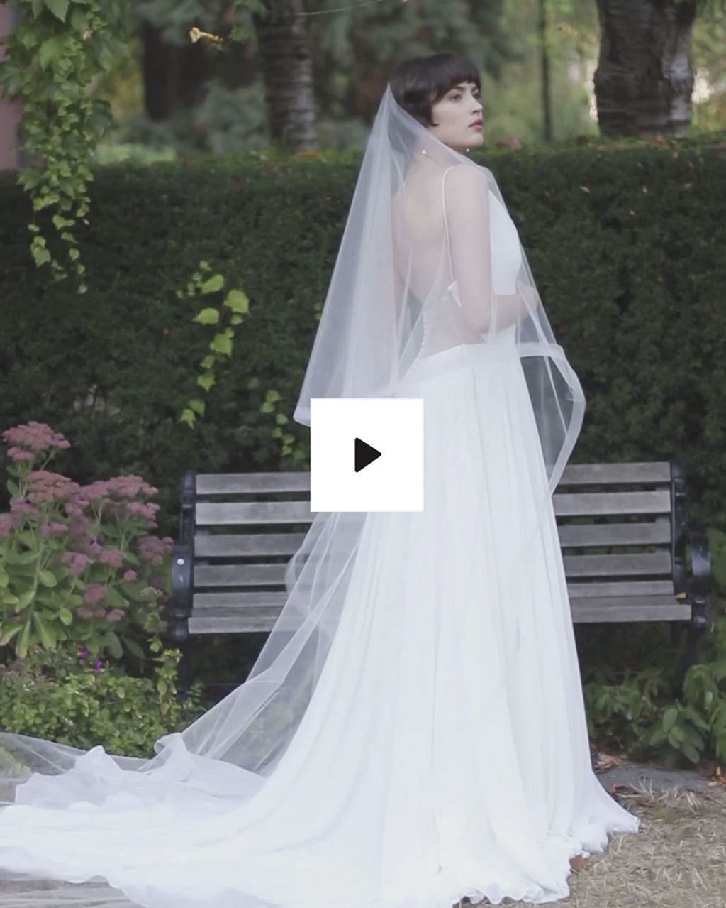 A wears the Zahra two layer veil in cathedral length in front of a flowering shrub.