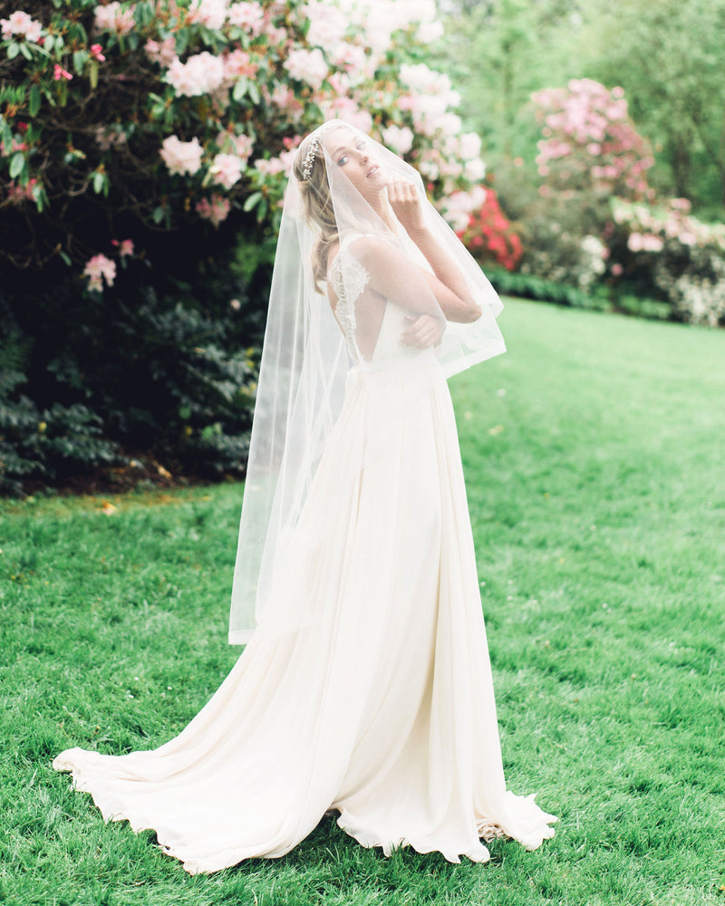 A bride wears the Zahra Horsehair Trim Veil in fingertip length, with the blusher worn to the front.